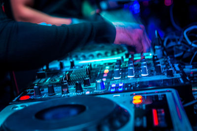 Cropped hand of dj playing music at nightclub