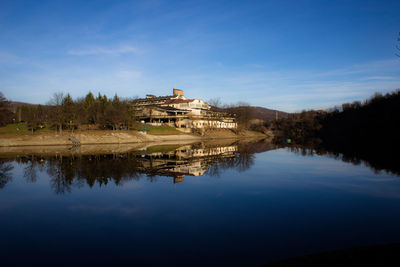 Buildings by lake against blue sky