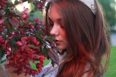 Close-up of woman smelling red flowers