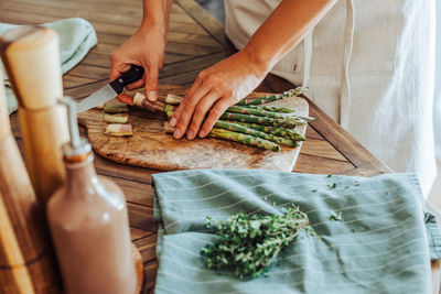 Female hands cutting asparagus on a cutting board on a table