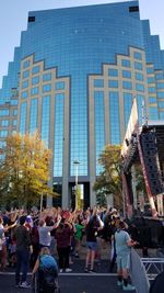 People on modern building in city against sky