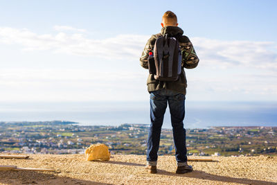 Rear view of man looking at cityscape against sky