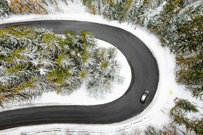 Aerial view of car on winding road in winter forest