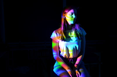 Woman wearing multi colored light painting against black background