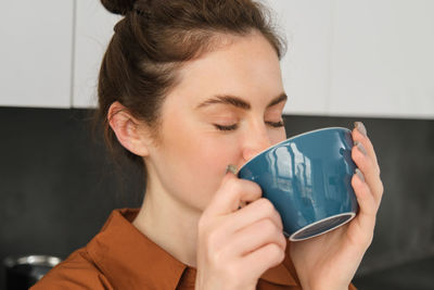 Close-up of woman holding coffee at home