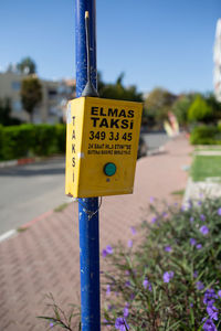 Close-up of information sign on pole by road against sky