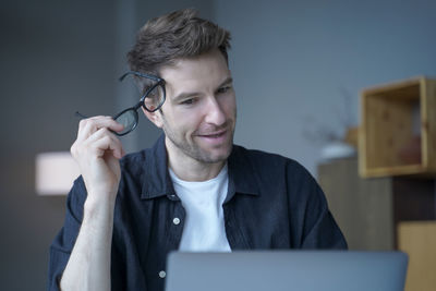 Businessman holding eyeglasses sitting at office