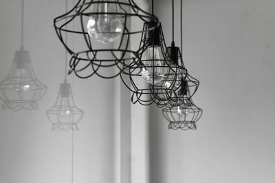 Close-up of illuminated light bulb hanging from ceiling