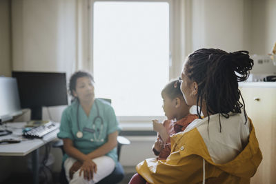 Woman with daughter visiting female pediatric in clinic