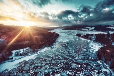 Snow covered landscape against sky during sunset