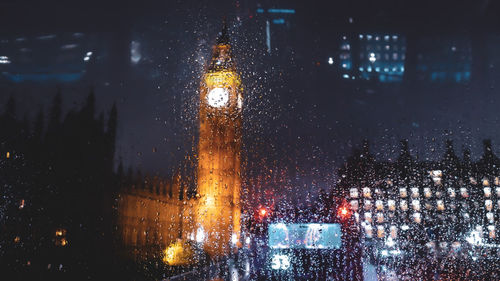 Illuminated buildings seen through wet window