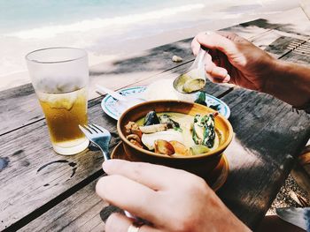 Midsection of person holding drink on table