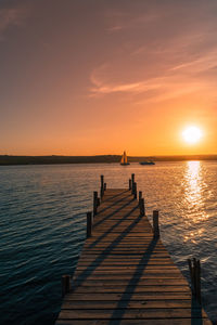 Pier over sea against sky during sunset