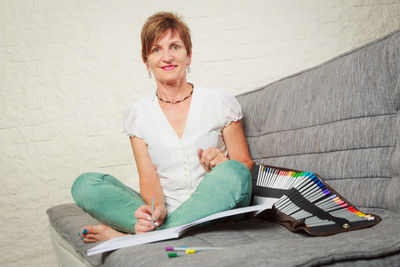 Portrait of a smiling young woman sitting against wall