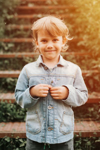 Portrait happy little kid boy holding a delicate pale lilac wildflower in his hands on nature