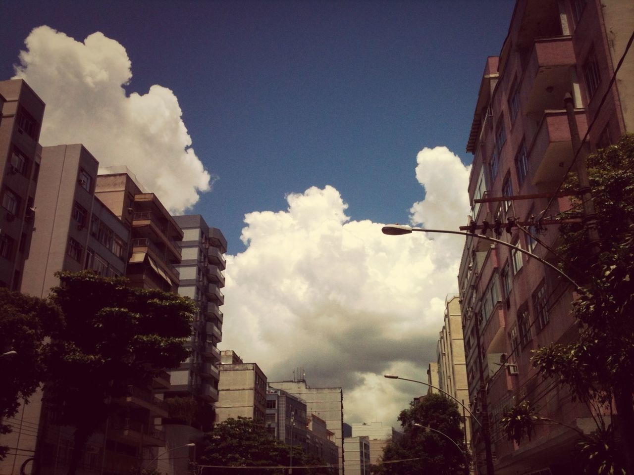 building exterior, architecture, built structure, sky, city, residential building, residential structure, cloud - sky, building, house, residential district, low angle view, cloud, tree, cloudy, street, city life, outdoors, street light, day