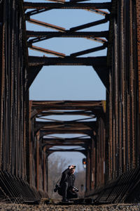 Side view of man standing on bridge against building