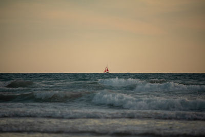 Sailboat sailing on sea against sky during sunset