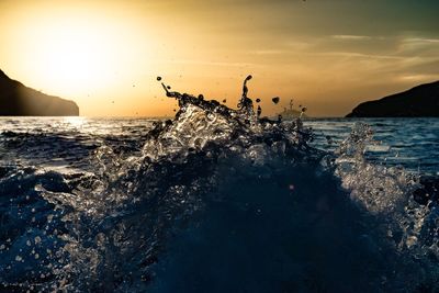 Sea waves splashing on rocks at sunset