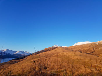 Scenic view of snowcapped mountains against clear blue sky