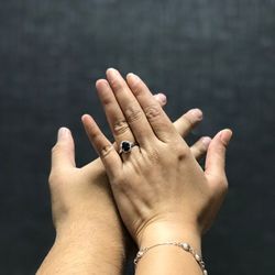 Midsection of couple holding hands against black background