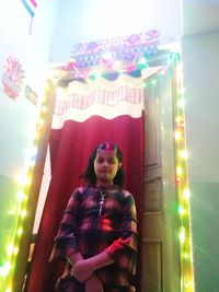 Portrait of smiling woman standing against illuminated lights