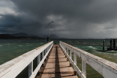 Pier over sea against cloudy sky