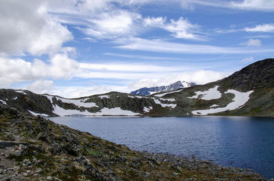 Scenic view of mountains and lake against cloudy sky