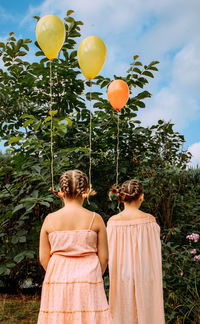 Rear view of women standing on balloons against trees