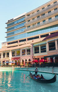 People in swimming pool against buildings in city