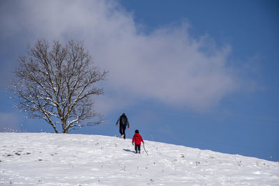 Rear view of people on snow covered land against sky