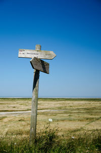 Cross on field against clear blue sky