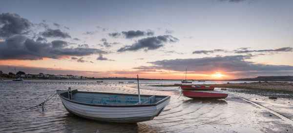 Boats moored on sea against sky during sunset