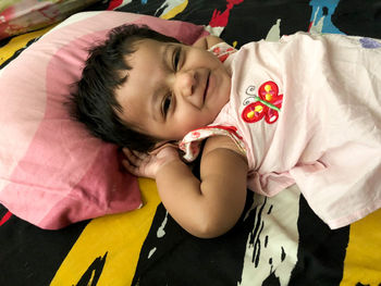 Happy girl waking up smiling looking at camera on parent bed at morning 