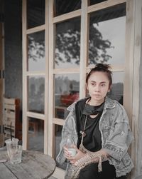 Portrait of young woman standing at table