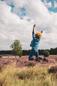 Full length of girl playing with arms raised on field