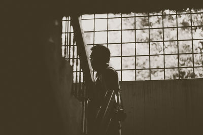 Man standing on staircase against window