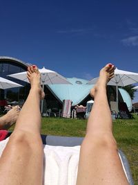 Low section of woman lying on grass against sky