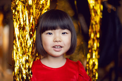 Portrait of a beautiful korean baby girl in a red dress at christmas with a gold decoration