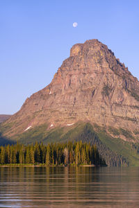 Sinopah mountain against blue sky with full moon, two medicine lake