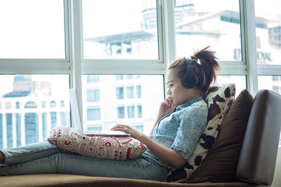 Side view of girl sitting on book at home