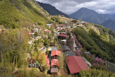 High angle view of houses on field by mountain against sky