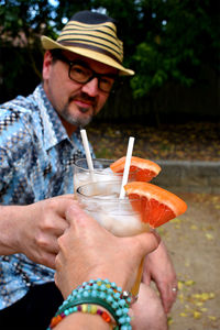 Portrait of man holding drink cheers