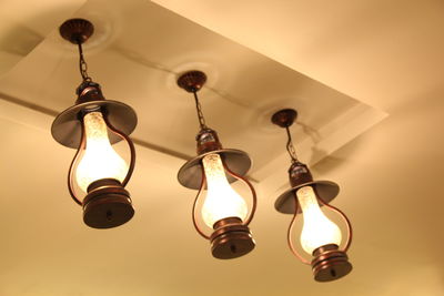 Low angle view of illuminated pendant lights hanging from ceiling at home