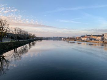 Scenic view of river by buildings against sky