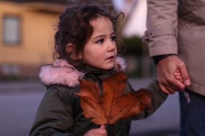 Daughter looking away while holding hands with father during autumn