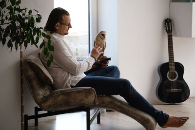 Man with owl at home. unusual pets and human animal friendship relationships. wild bird on hand