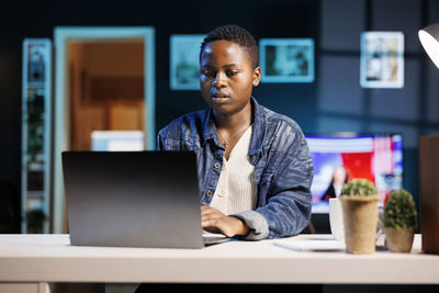 Portrait of young man using laptop at office