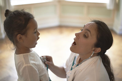 General practitioner using a stethoscope during check-up a young girl