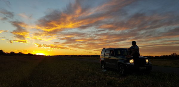 Car on field against sky during sunset